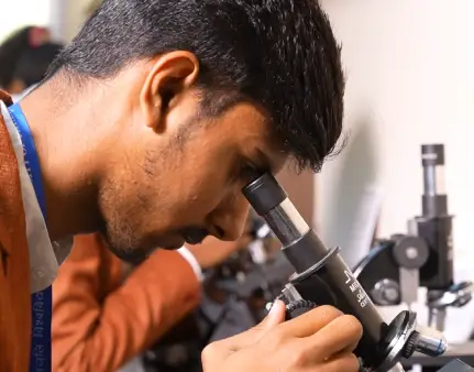 Student using a microscope in an advanced laboratory at the University of Patanjali for scientific research training